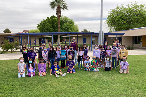 Students in purple posing outside